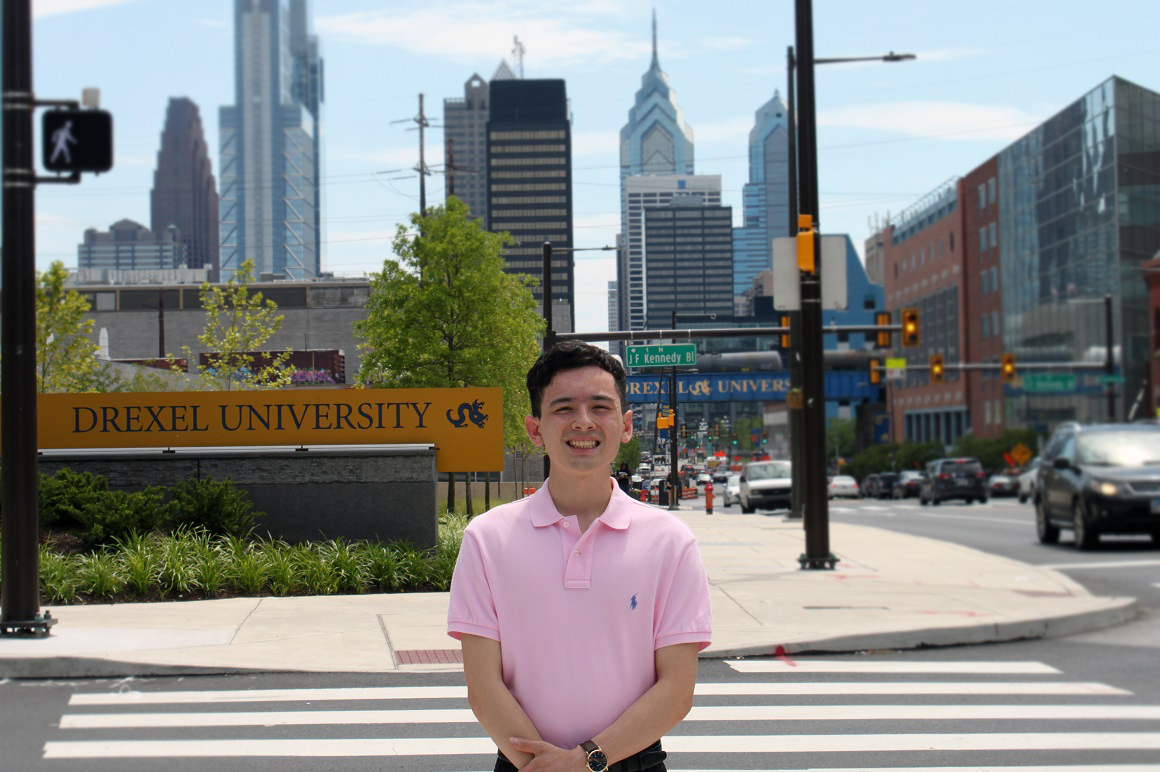Student standing on Market Street with the Philadelphia skyline in the background